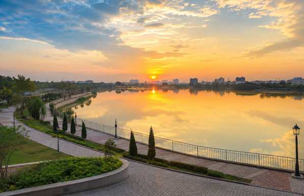 Photorealistic sunrise view of Mehrun Lake in Jalgaon with calm water, landscaped promenade, lush greenery, and city skyline representing Resume Writing Services Jalgaon by Bright Future Resume.