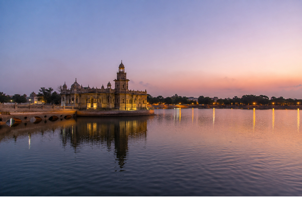 Lakhota Lake and Lakhota Palace in Jamnagar with calm water, historic architecture, clear sky, and no crowd.